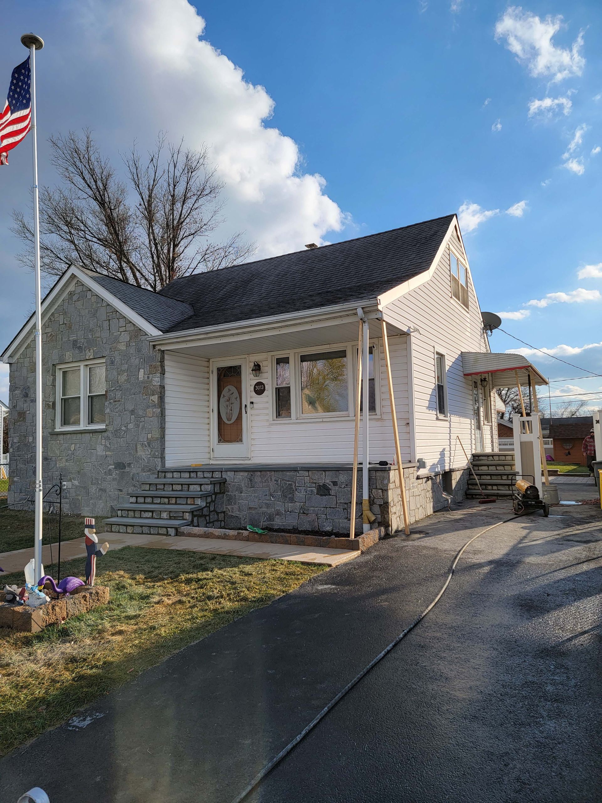 a small white house with a black roof and an american flag in front of it .