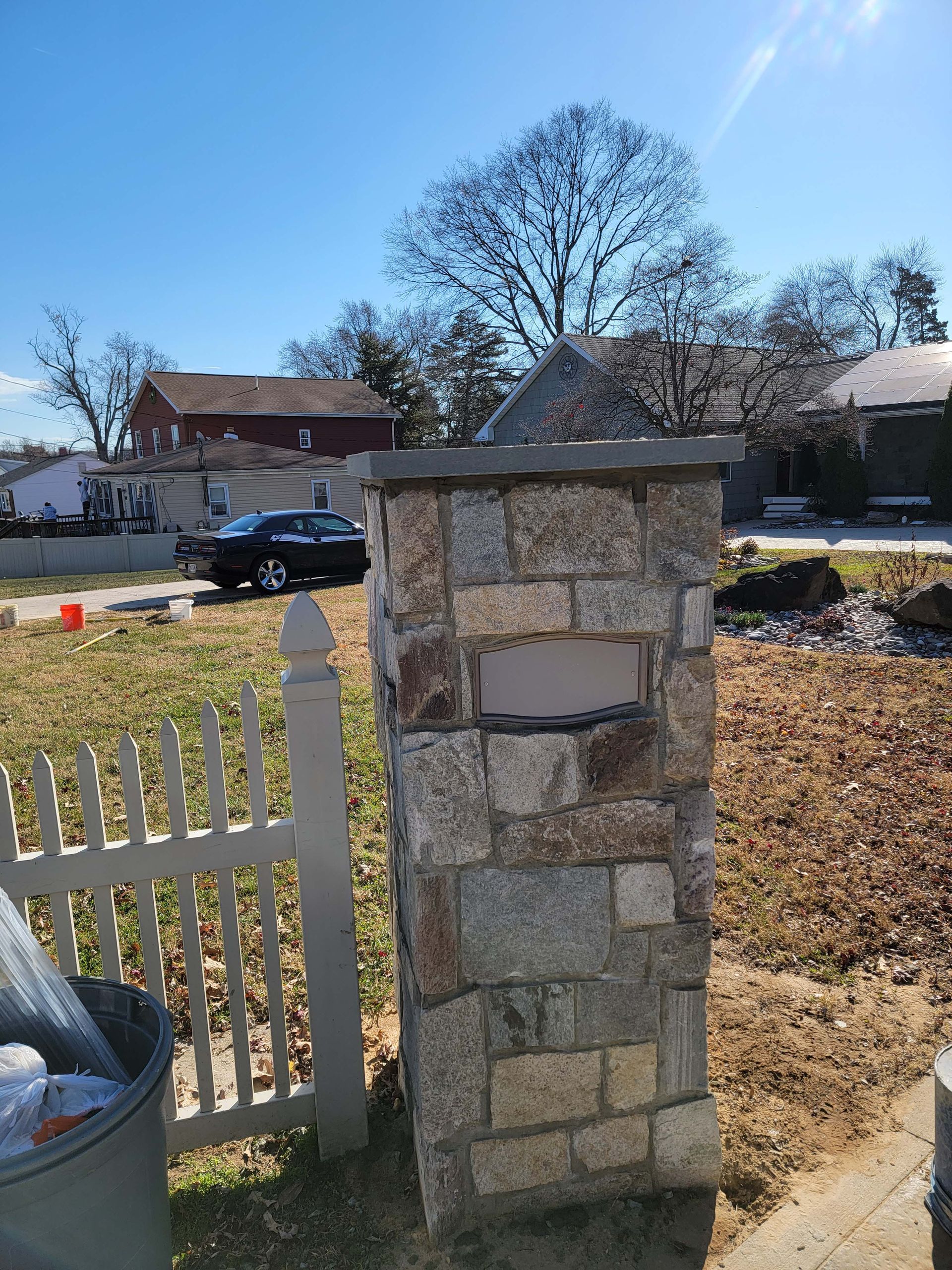 a white picket fence surrounds a stone pillar