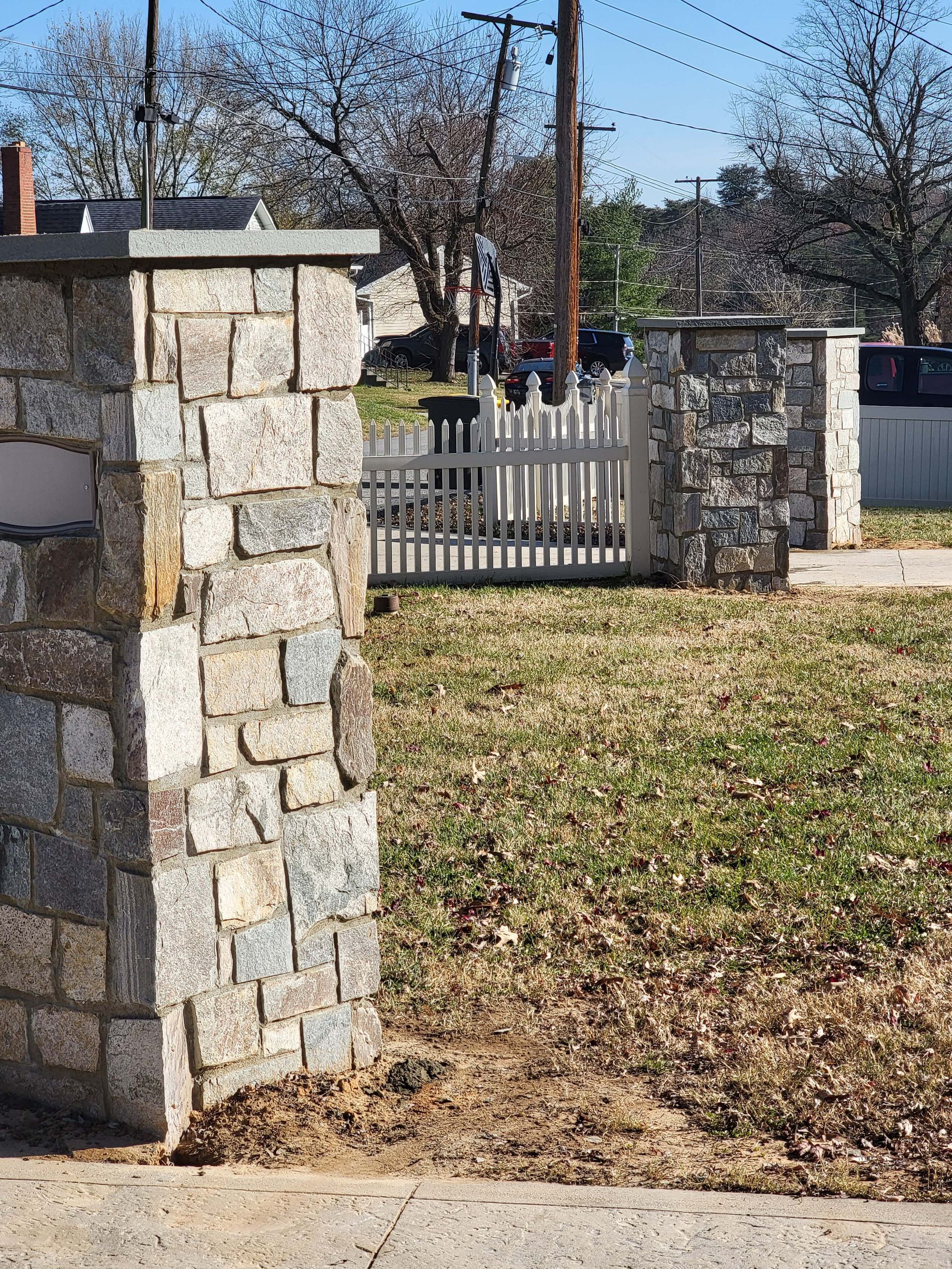 a stone wall with a white picket fence in the background