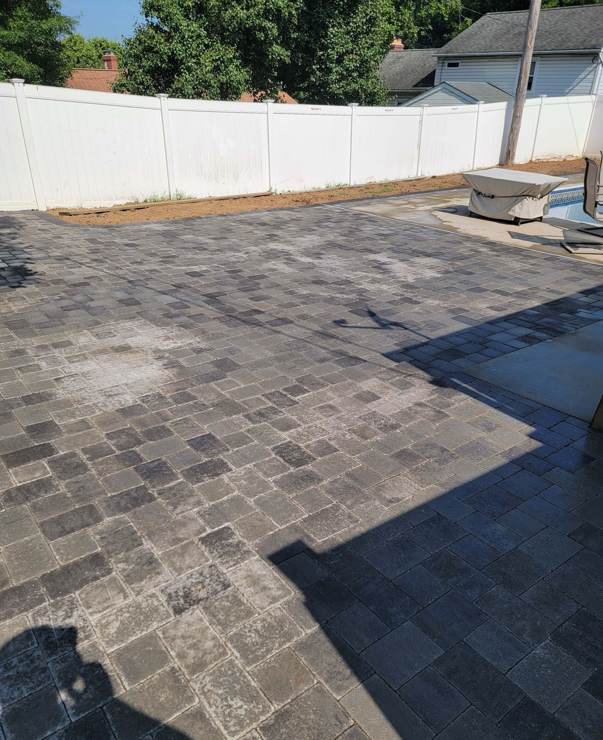 a brick driveway with a white fence in the background .