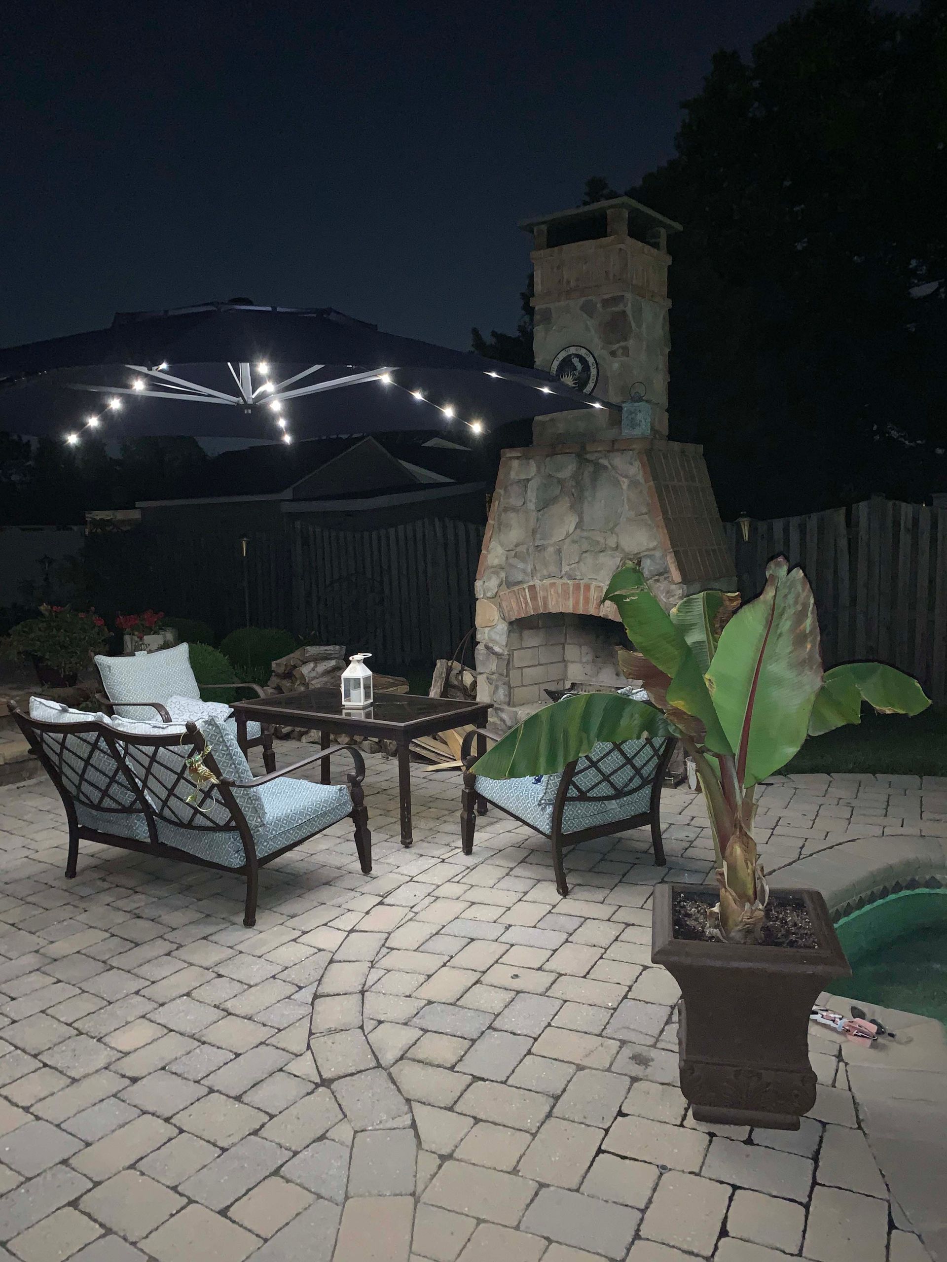 a patio with furniture and a fireplace at night