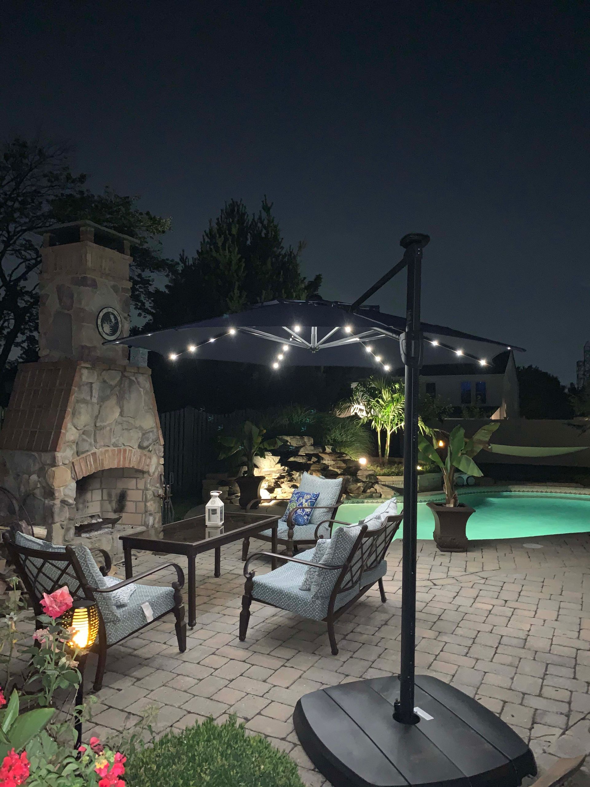 a patio with a umbrella and a fireplace at night .