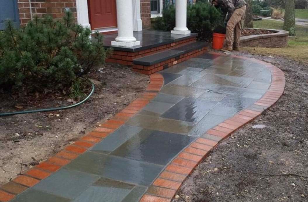 a man is standing on a brick walkway in front of a house .