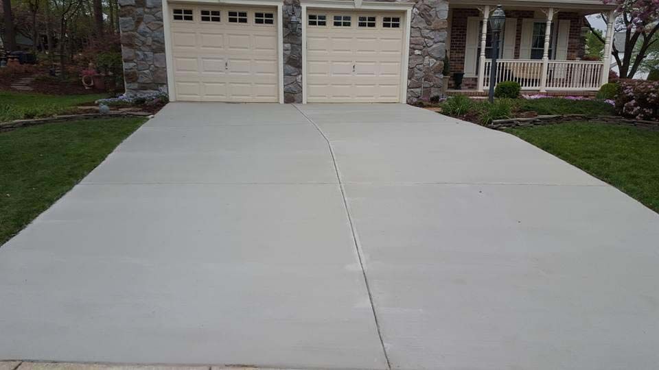 a concrete driveway leading to a house with two garage doors .