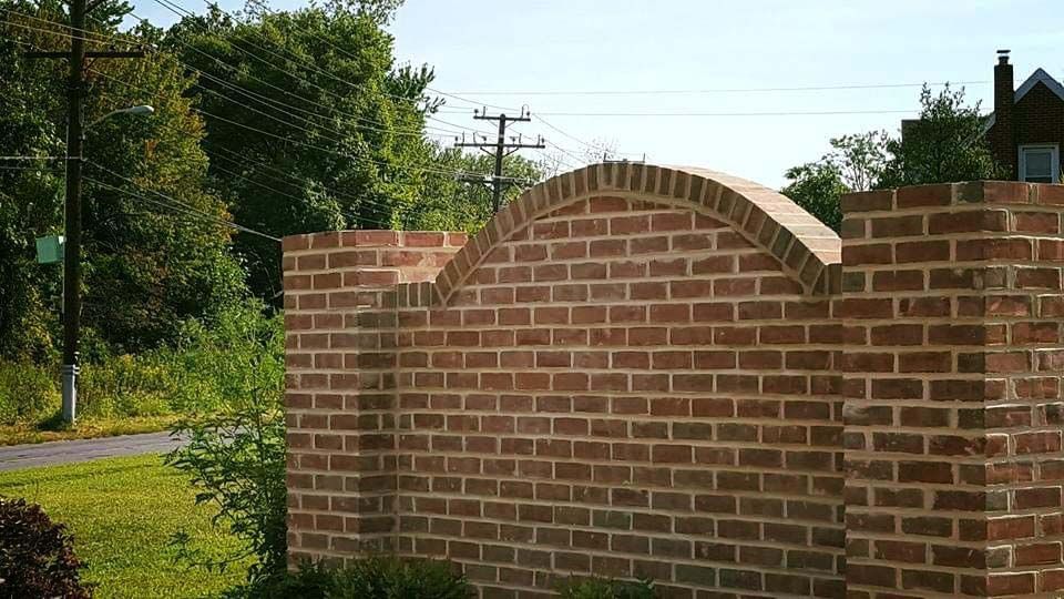 a large brick wall with a curved top is surrounded by grass and trees .