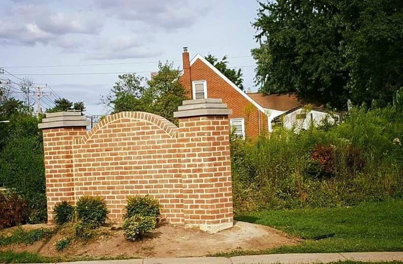 a brick wall with a house in the background