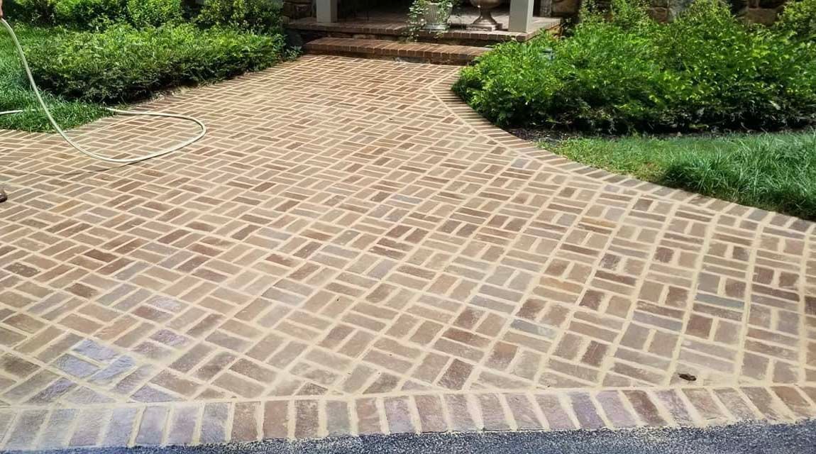 a brick walkway leading to a house with a sprinkler on it .