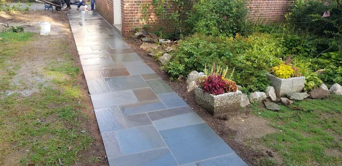 a stone walkway leading to a house in a garden .