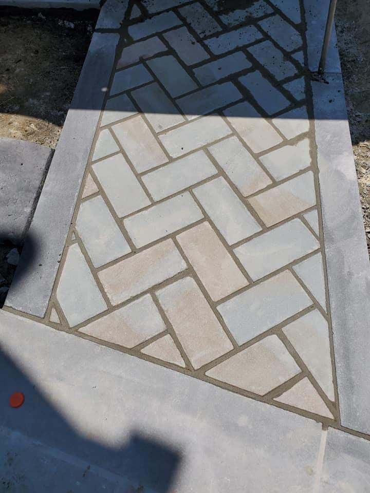 a brick walkway with a herringbone pattern is being built .