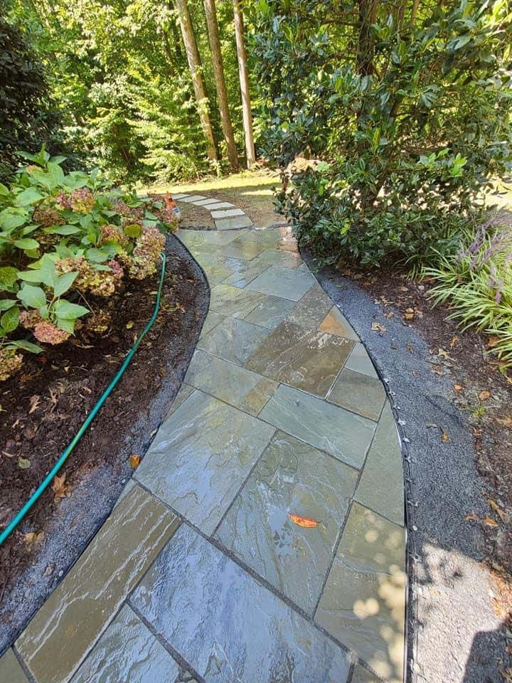 a stone walkway in a garden with a hose attached to it .