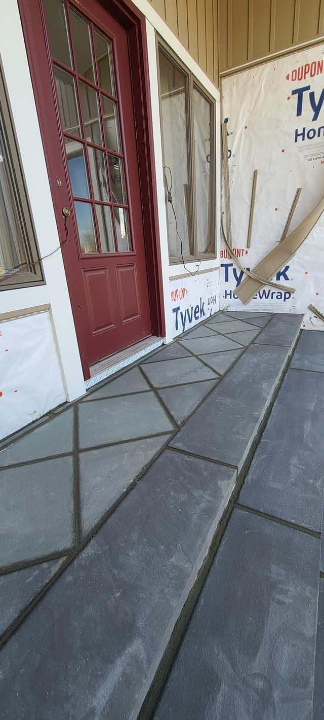 a porch with a red door and a gray tile floor .
