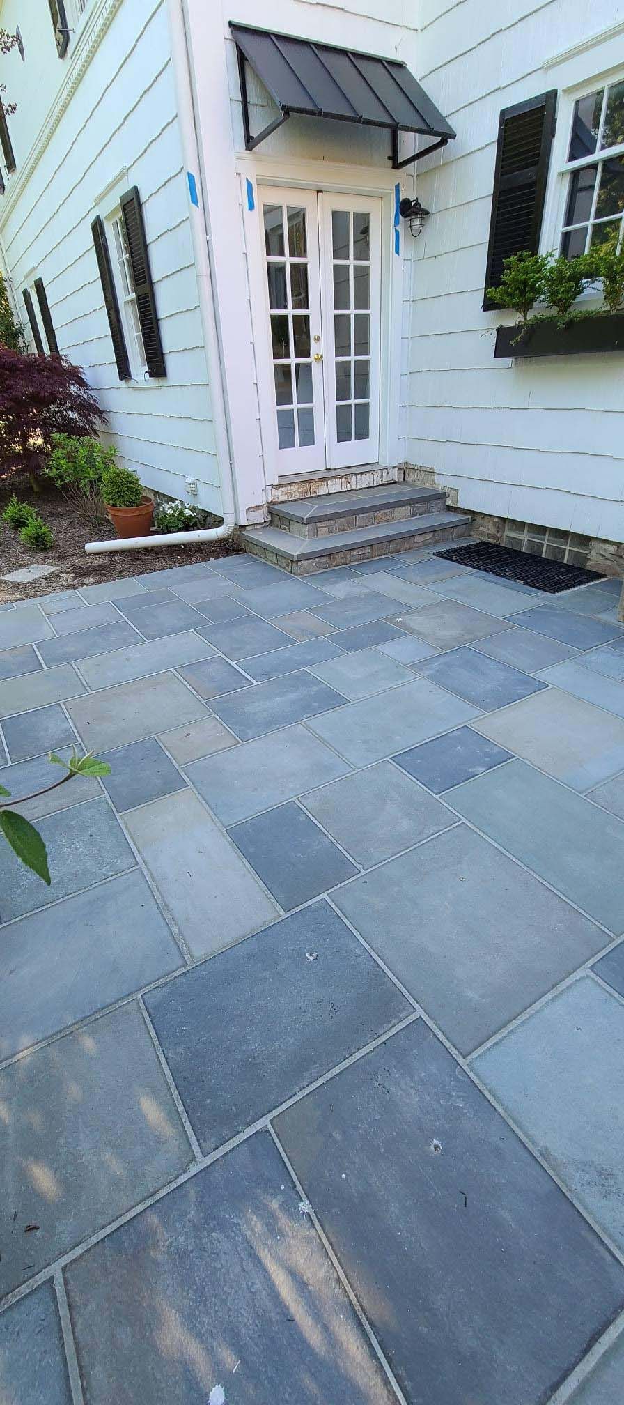 a stone patio in front of a white house with a canopy over the door .