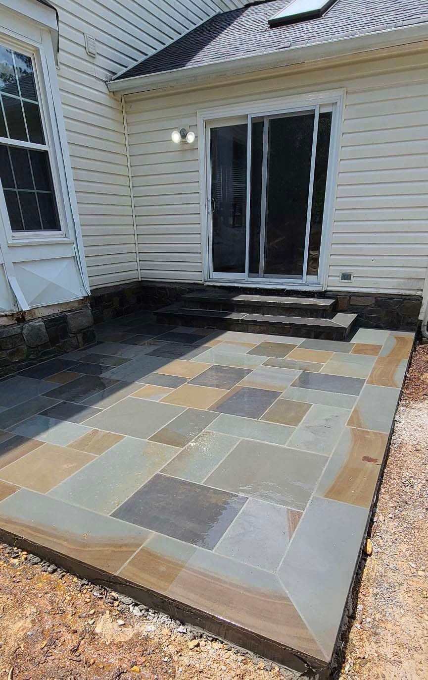 a patio with stairs and a sliding glass door in the backyard of a house .