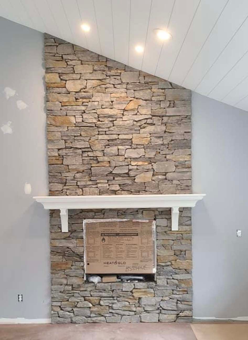a living room with a stone fireplace and a white mantle .