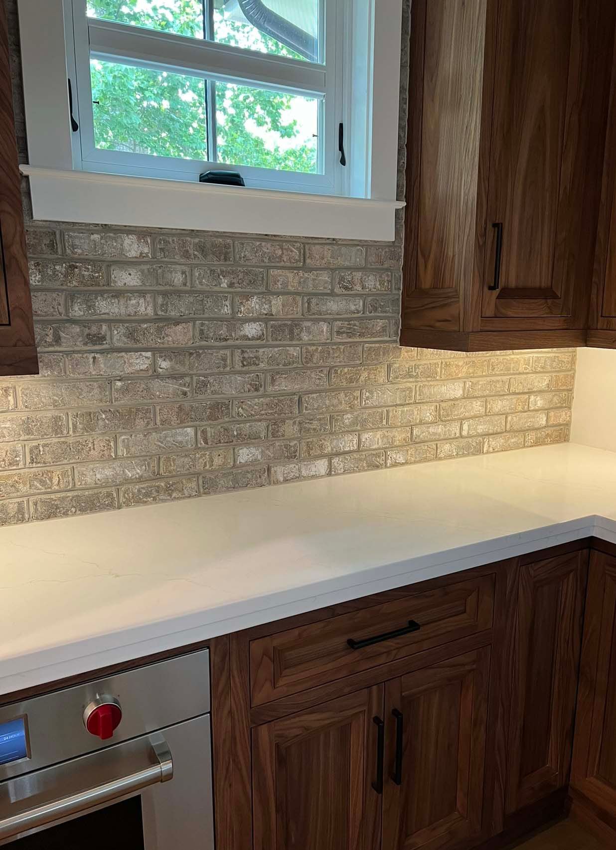 a kitchen with wooden cabinets , a stove , and a window .