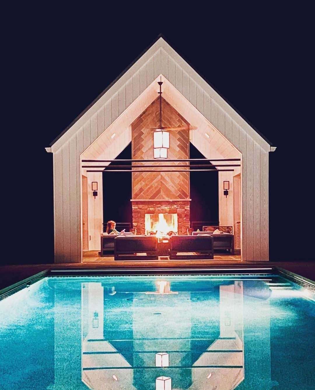 a house with a fireplace and a swimming pool at night