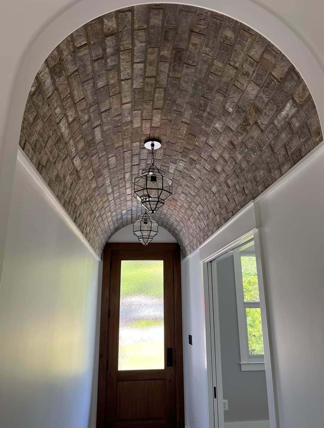 a hallway with a brick arched ceiling and a door .