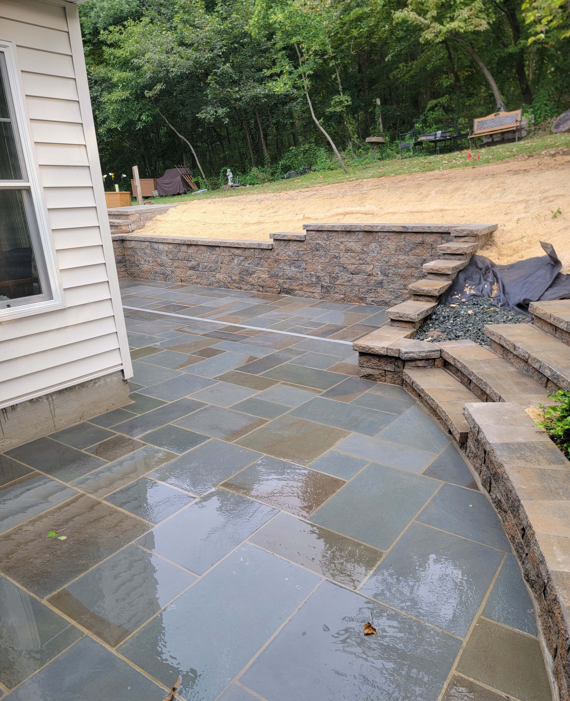 a patio with stairs and a stone wall next to a house .