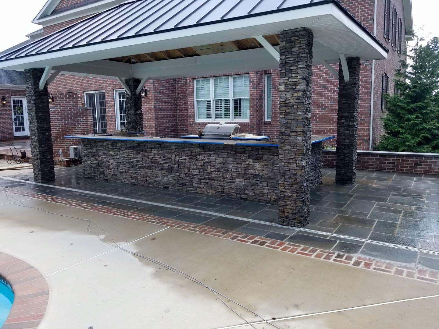 a brick house with a covered patio area and a grill .
