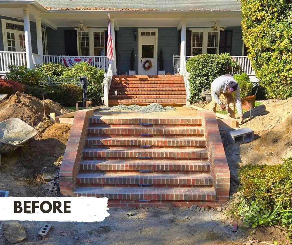 Brick steps under construction leading to the porch of a blue house. A worker places bricks while the area around the steps is unfinished.