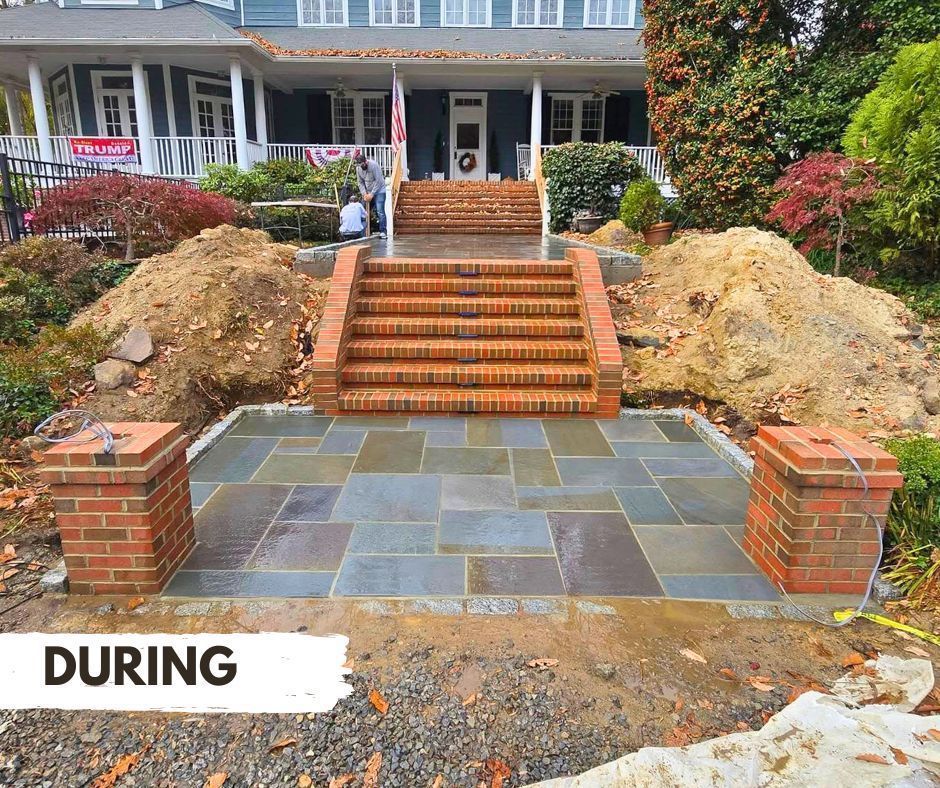Brick steps and patio under construction in front of a two-story house. Two brick pillars flank the patio. Dirt piles are visible.