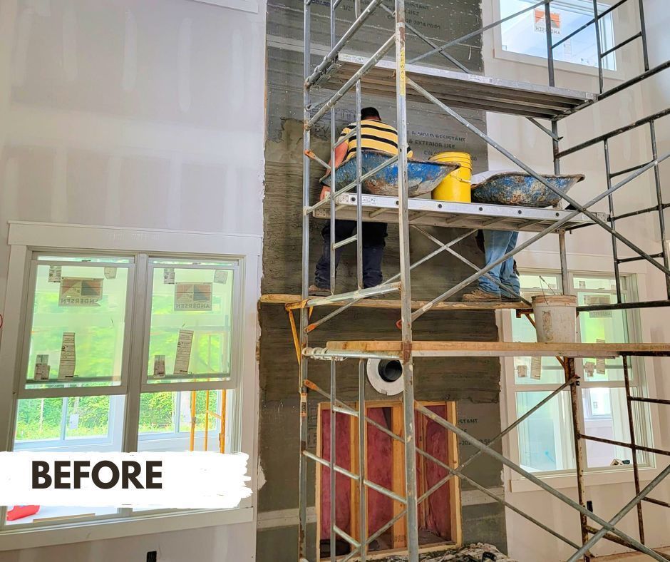 Construction workers applying textured finish to a tall wall, working from scaffolding.  Gray wall material, yellow hard hats, and bright sunlight.