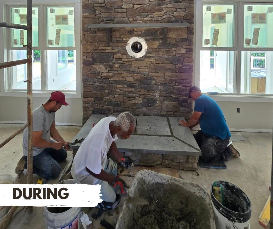 Three men working on a stone fireplace during construction. They are kneeling, applying material and working on the hearth.