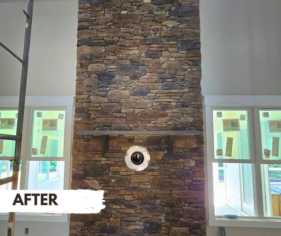 Stone-covered chimney in a room with windows.  It has a mantle and circular vent;