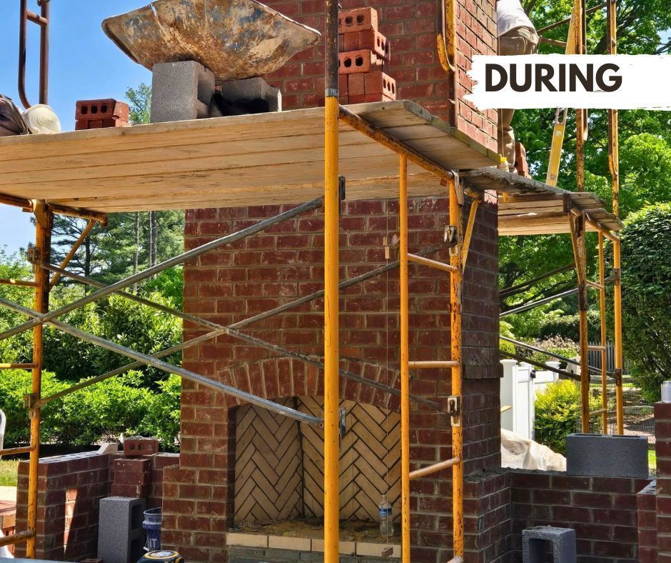 Brick chimney being built during construction, with scaffolding, red bricks, and a herringbone pattern on the fireplace interior.