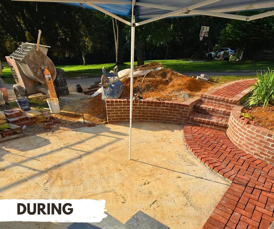 Construction in progress; brick patio and retaining walls being built under a canopy.
