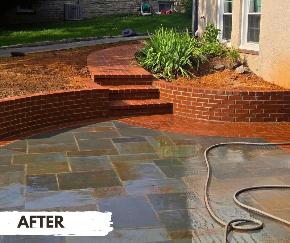 Finished patio with brick retaining wall and steps leading to a brick walkway. Blue-gray flagstone pavers make up the patio.