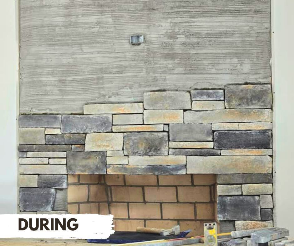 Construction of a fireplace surround: Stone veneer being applied to a wall, covering the brick firebox.