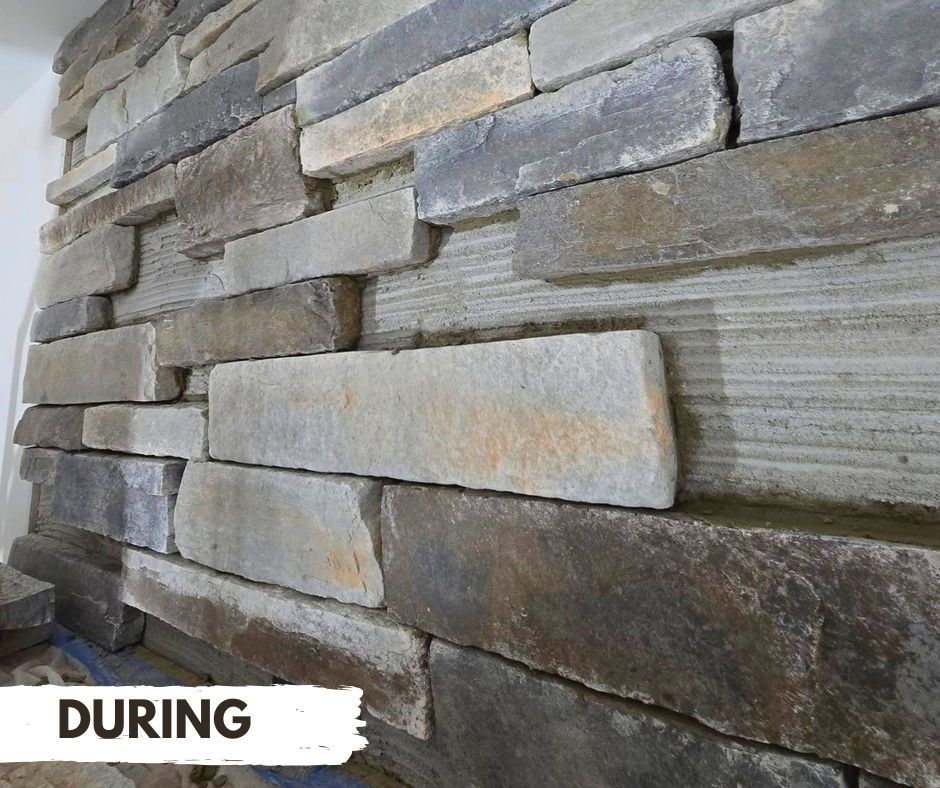 During installation of stacked stone veneer on a wall, showing different shades of stone being placed.