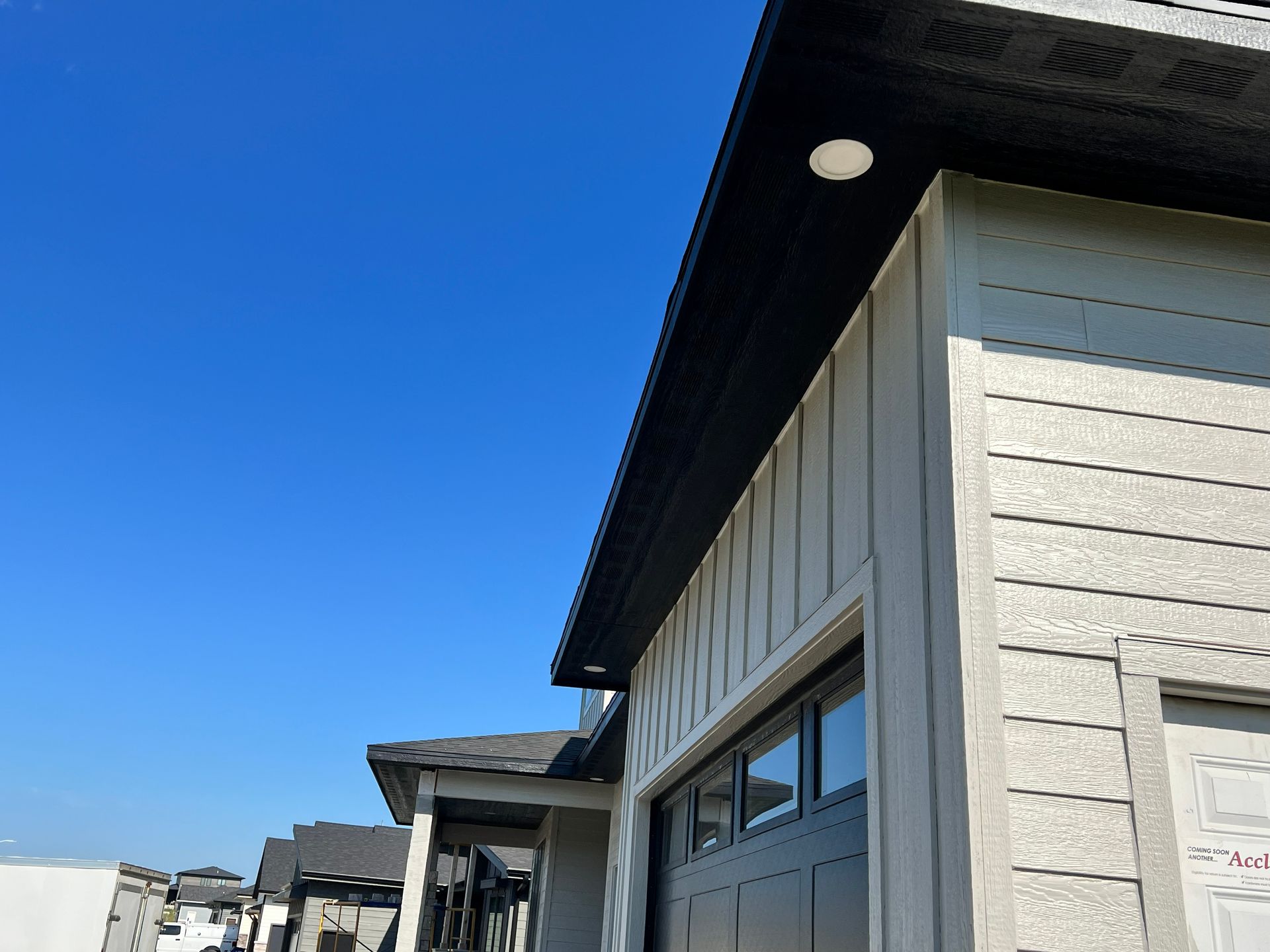 Exterior view of a house with a black roof, white siding, and blue sky.