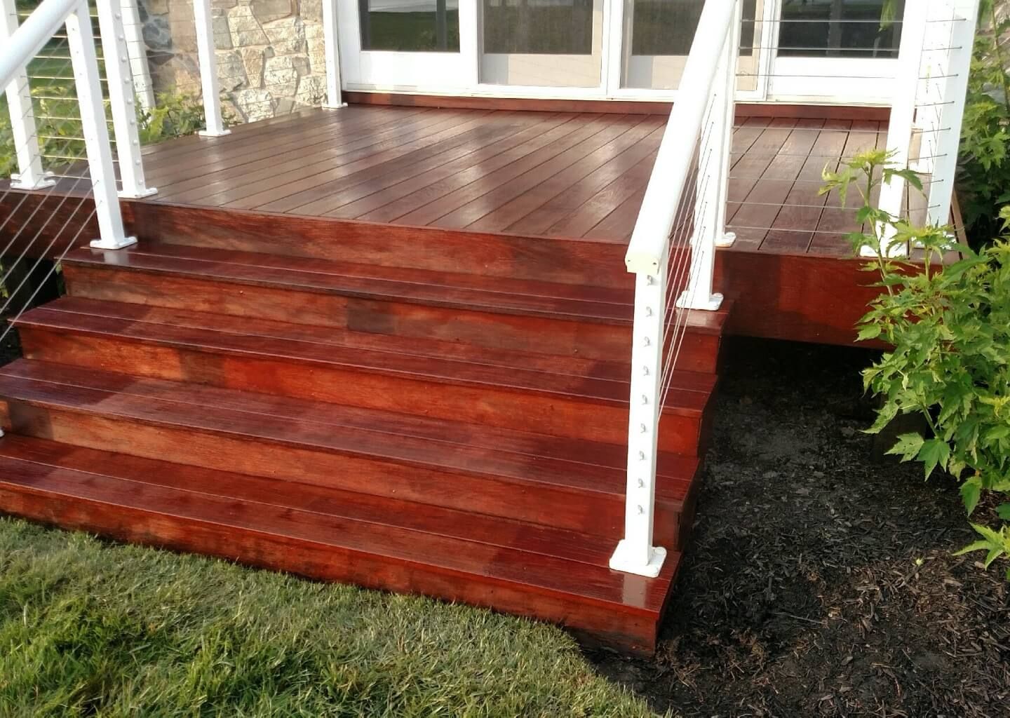 Red wooden front porch steps with white railings leading to a house entrance