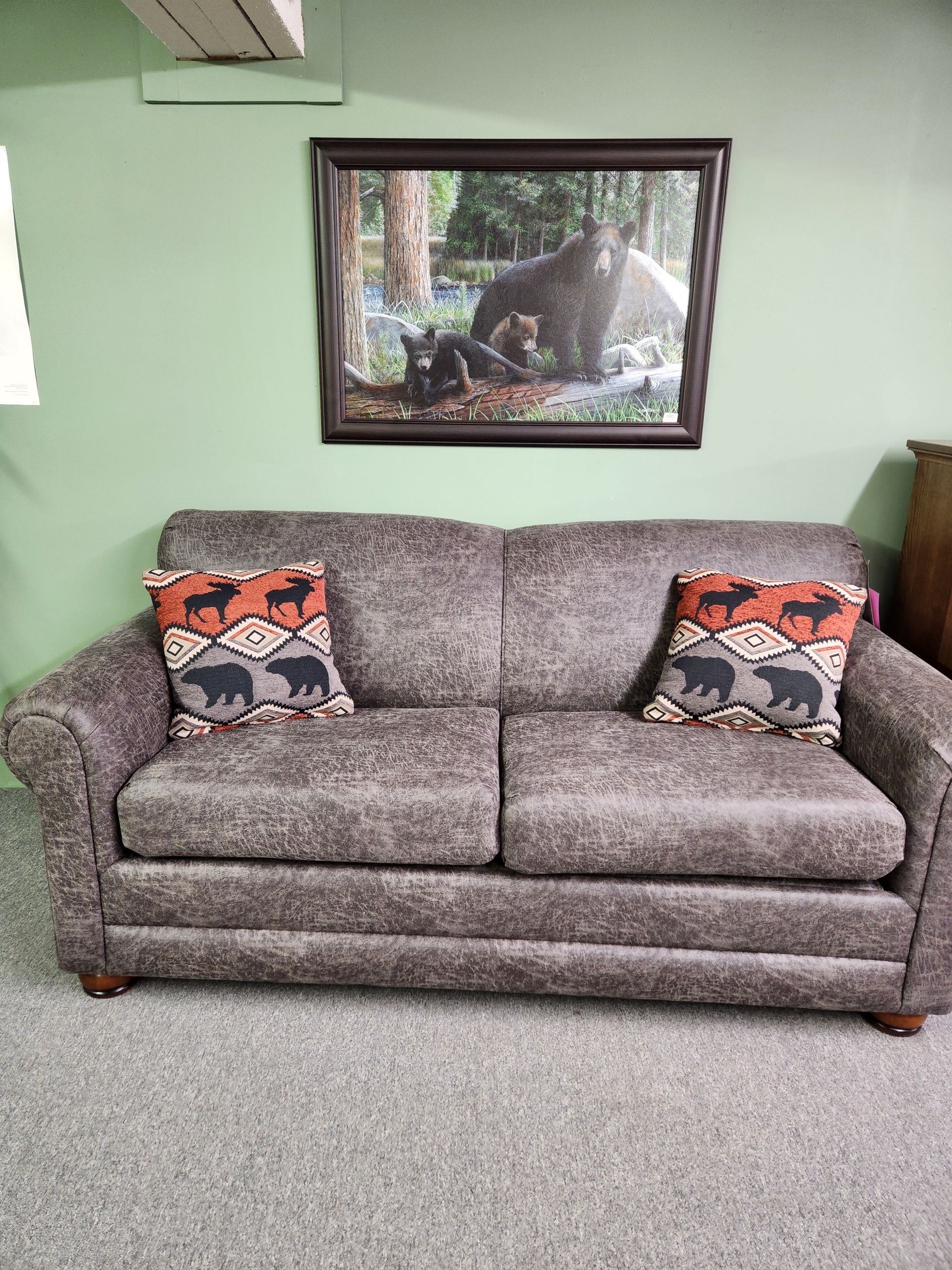 A couch with pillows and a picture of a bear on the wall.