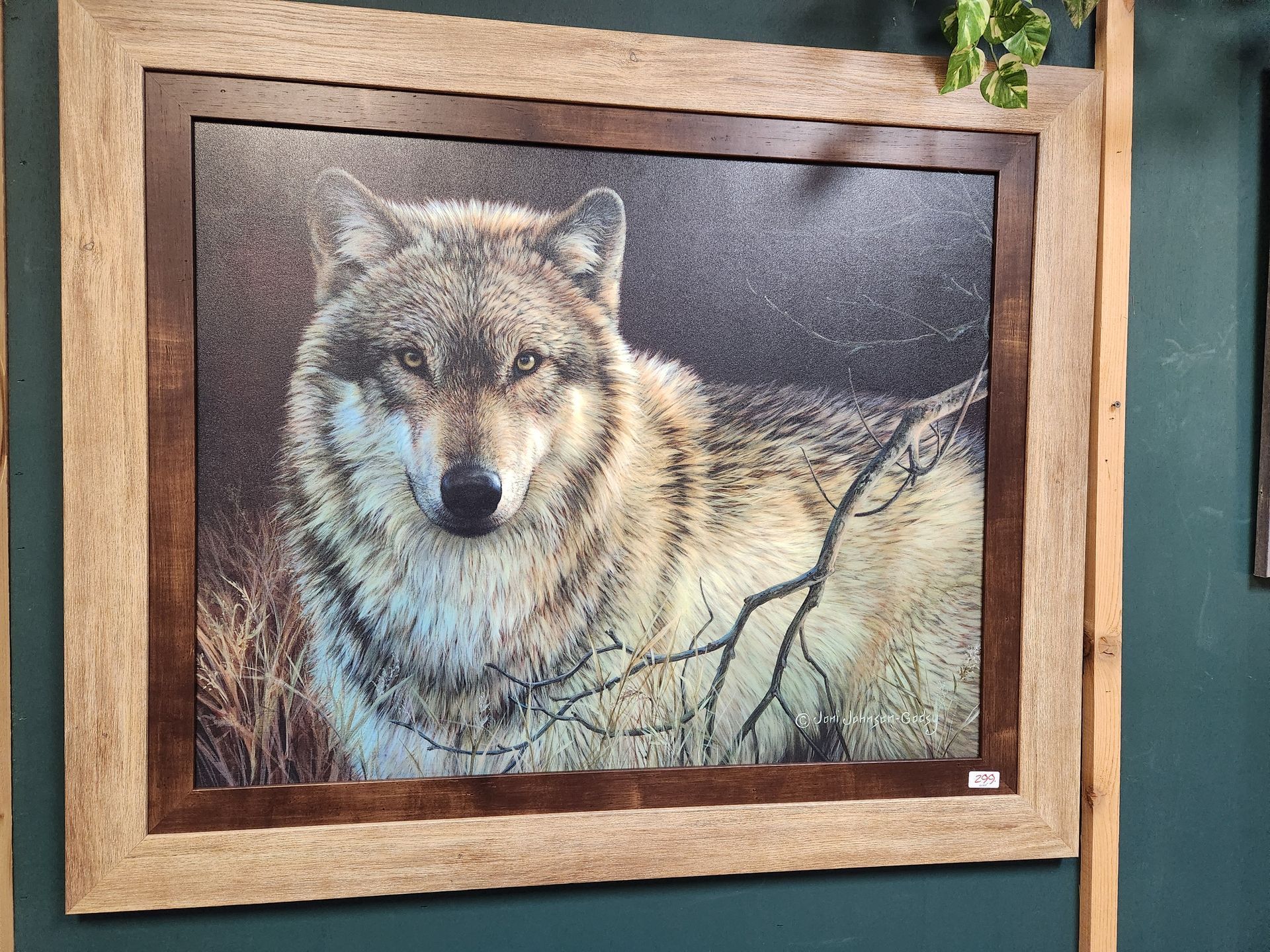 A painting of a wolf in a wooden frame on a wall.