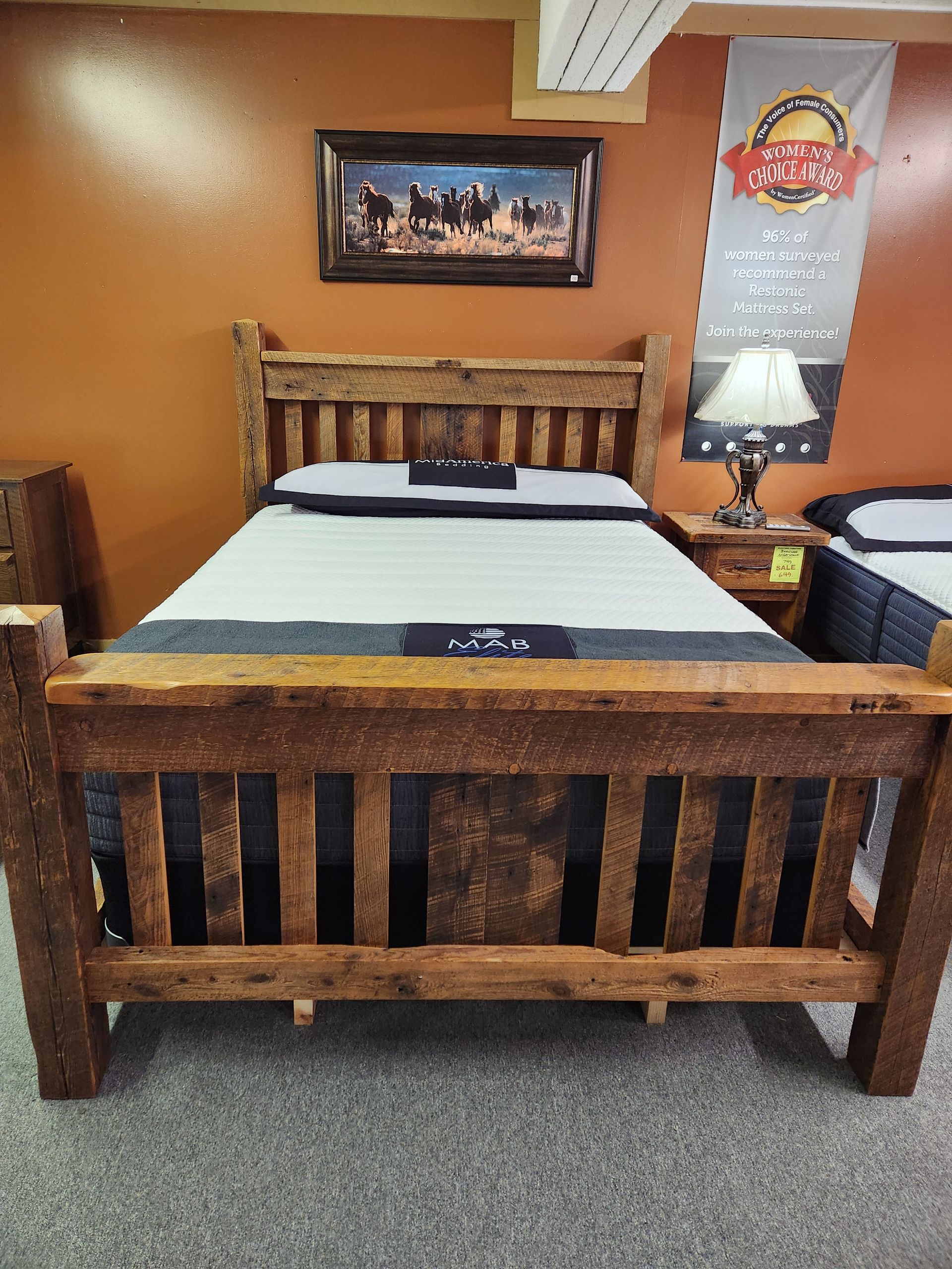 A bed with a wooden frame is sitting in a room with a painting on the wall above it.