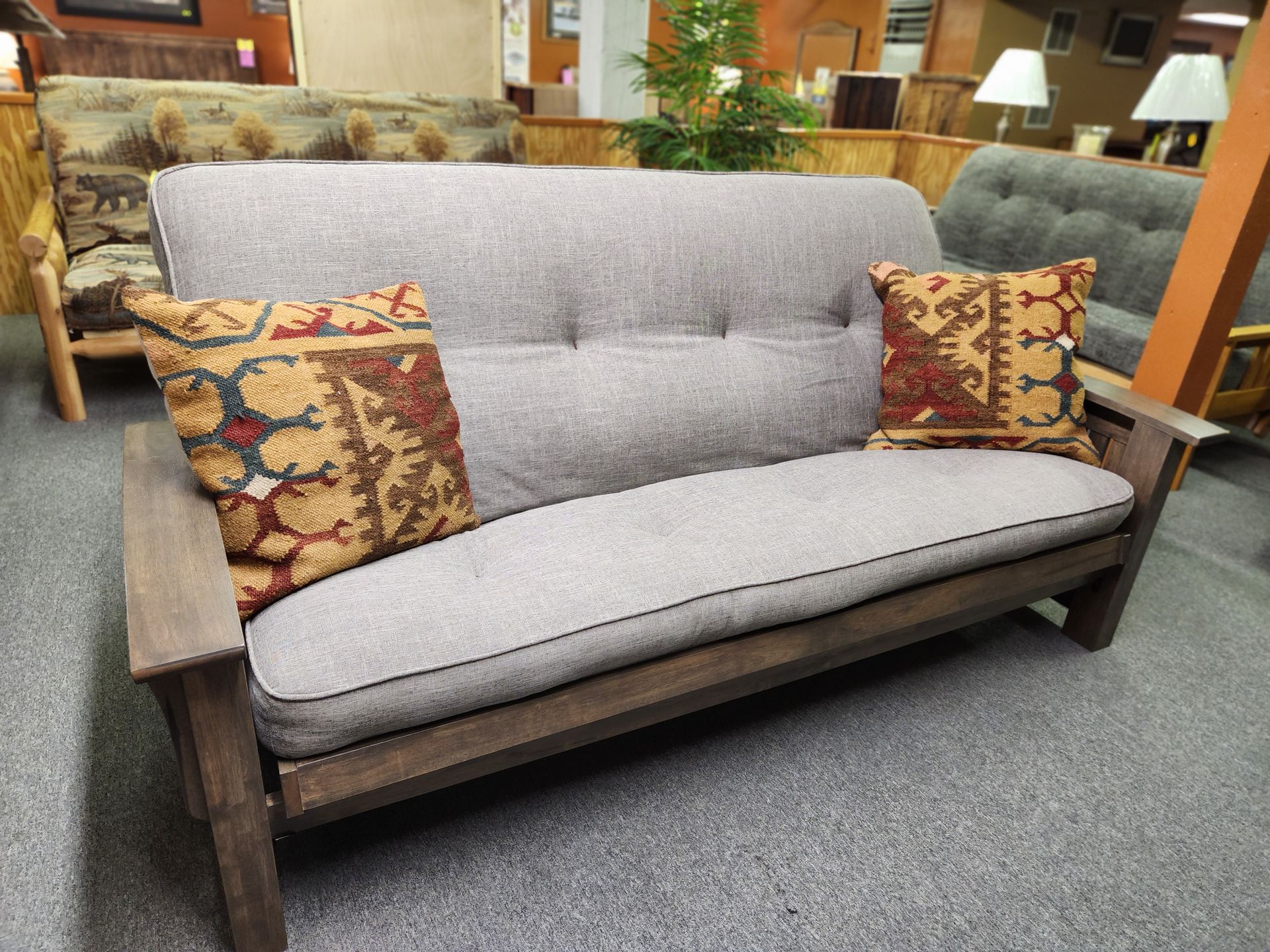 A futon with two pillows on it is sitting in a living room.