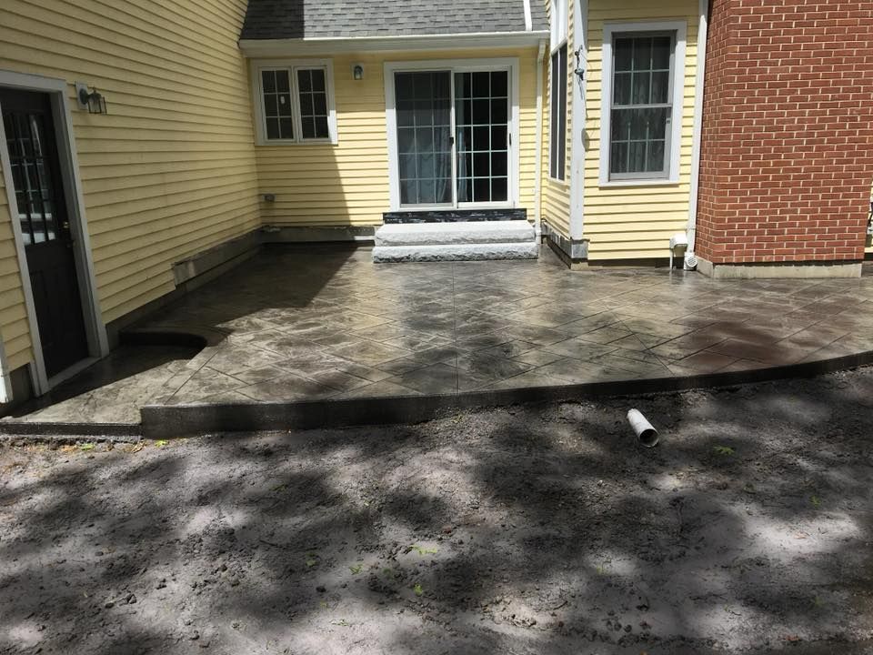 A concrete patio in front of a house with a sliding glass door.