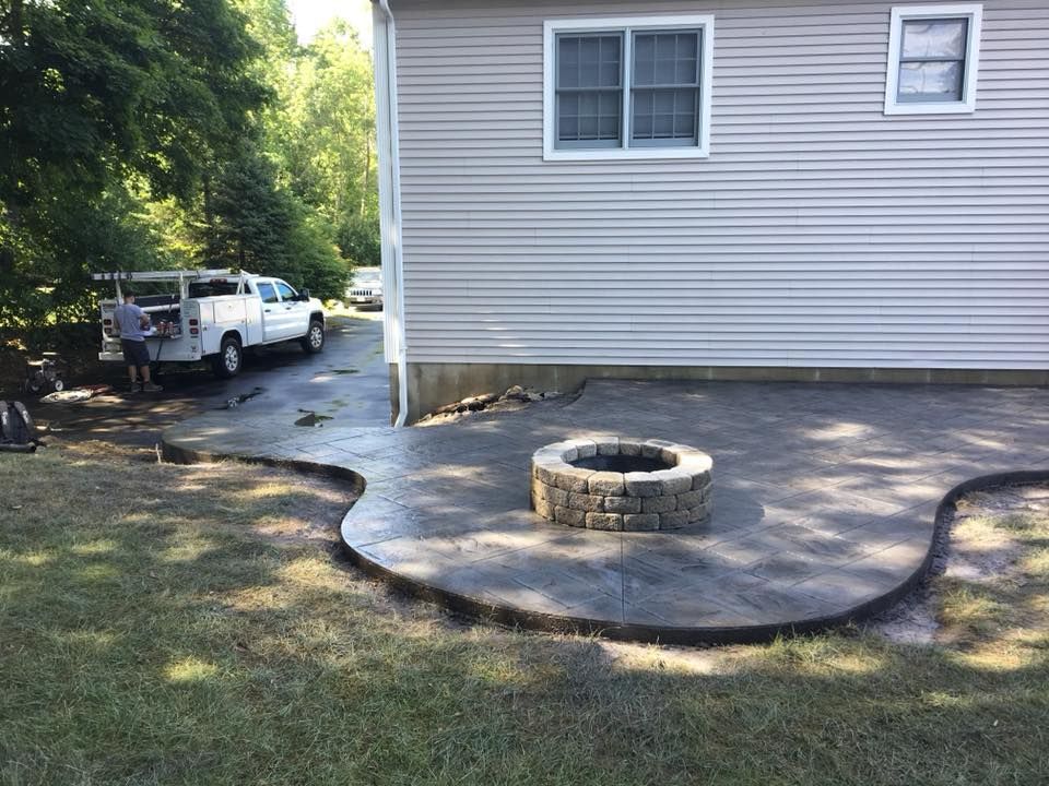 A fire pit is sitting on a concrete patio in front of a house.