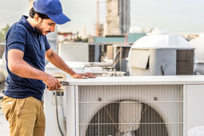 Technician in blue cap inspecting rooftop air conditioner unit