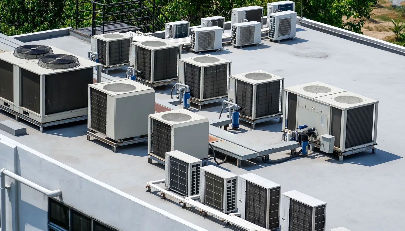 Rooftop with multiple HVAC air-conditioning units and vents on a flat white roof.