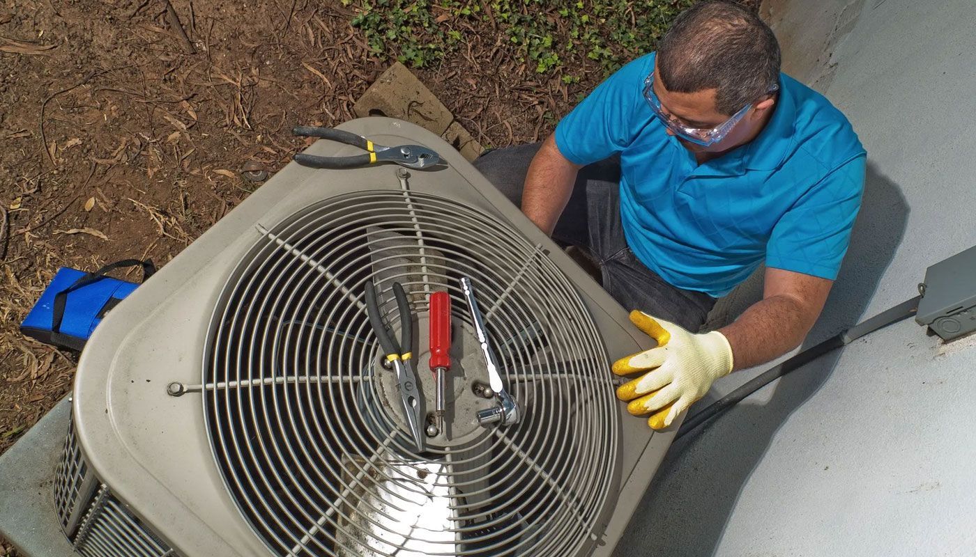 Technician in blue shirt servicing a large industrial fan outdoors