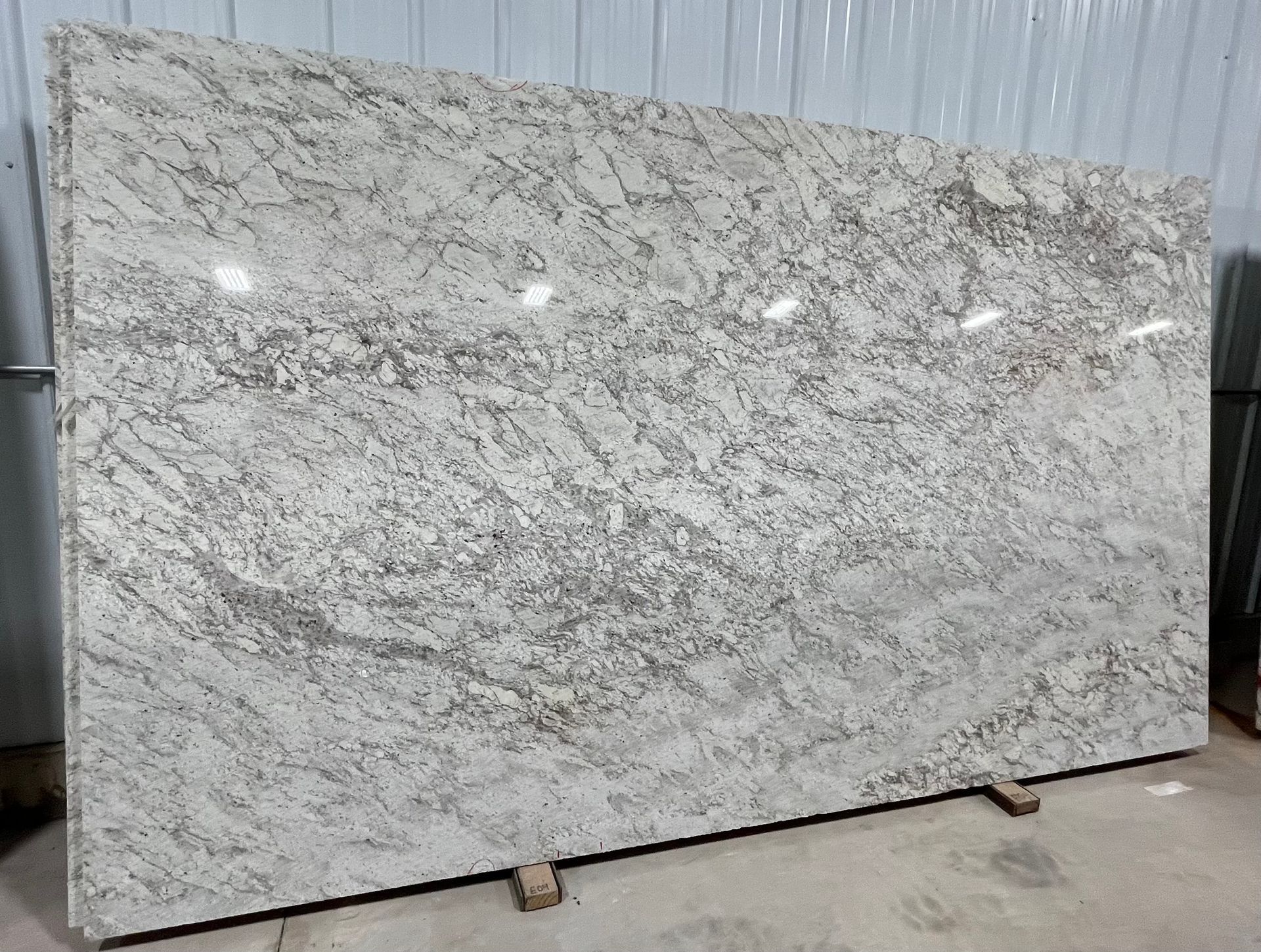 A large white granite slab is sitting on top of a cement floor.