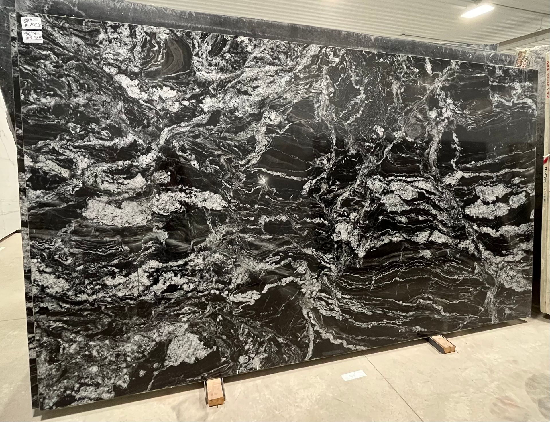 A black and white granite slab is sitting on a wooden pallet in a warehouse.