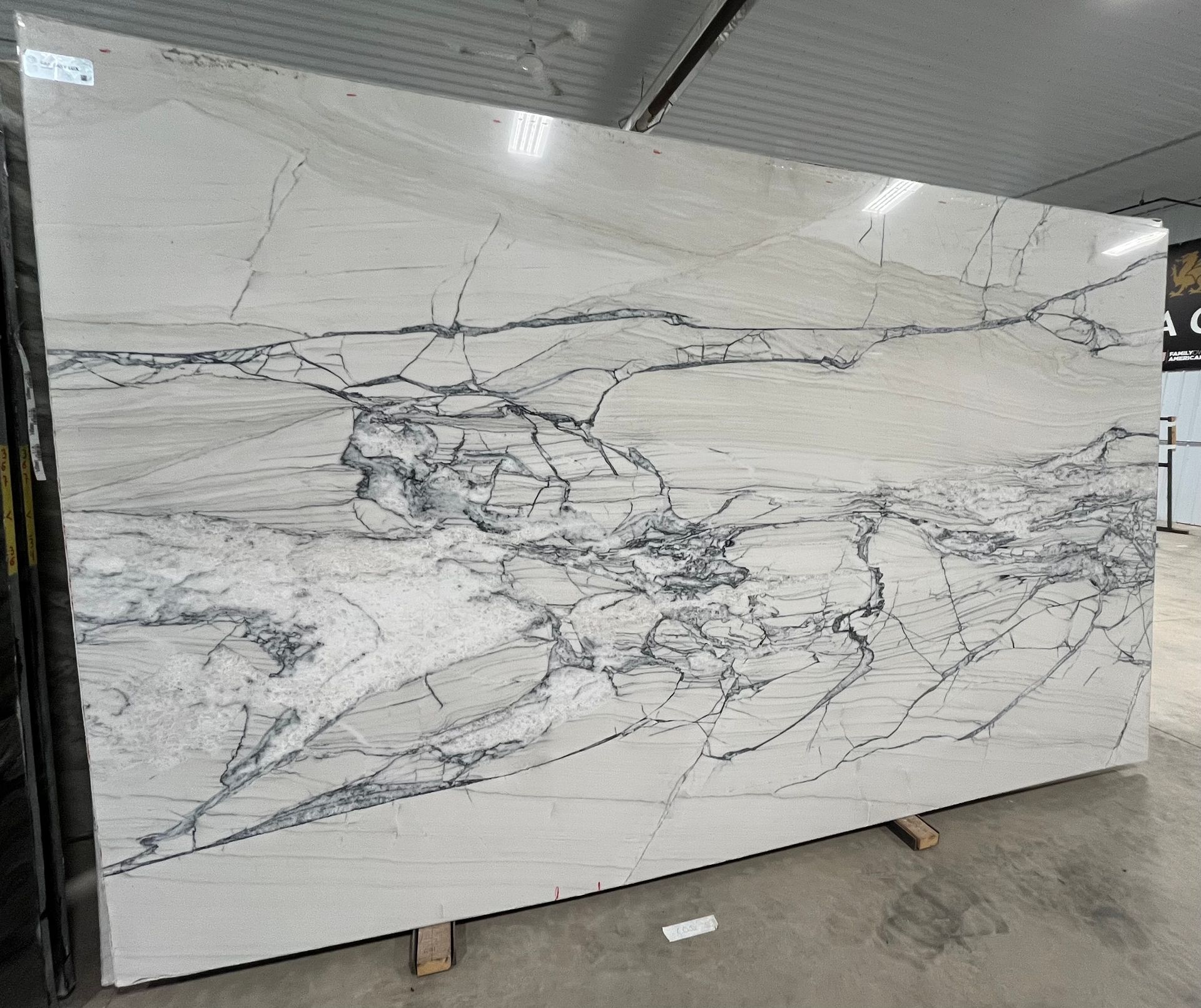 A large white marble slab is sitting on a wooden pallet in a warehouse.