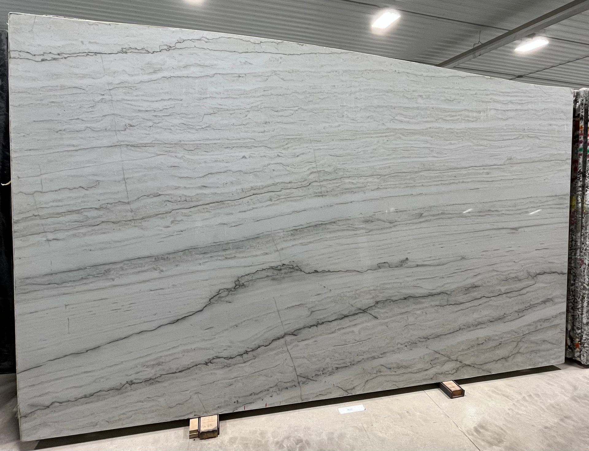 A large white granite slab is sitting on top of a concrete floor in a warehouse.