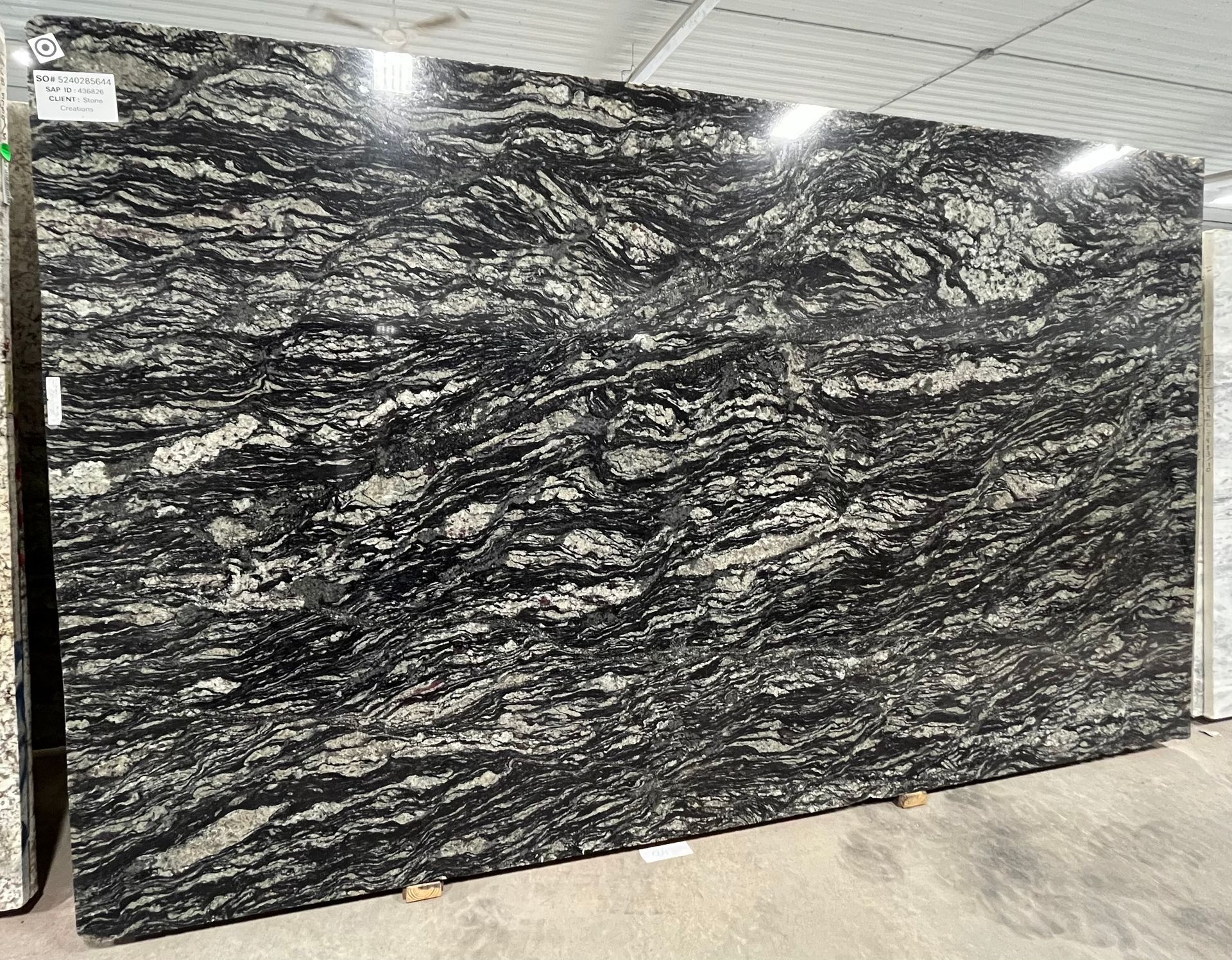 A large black granite slab is sitting on the ground in a warehouse.