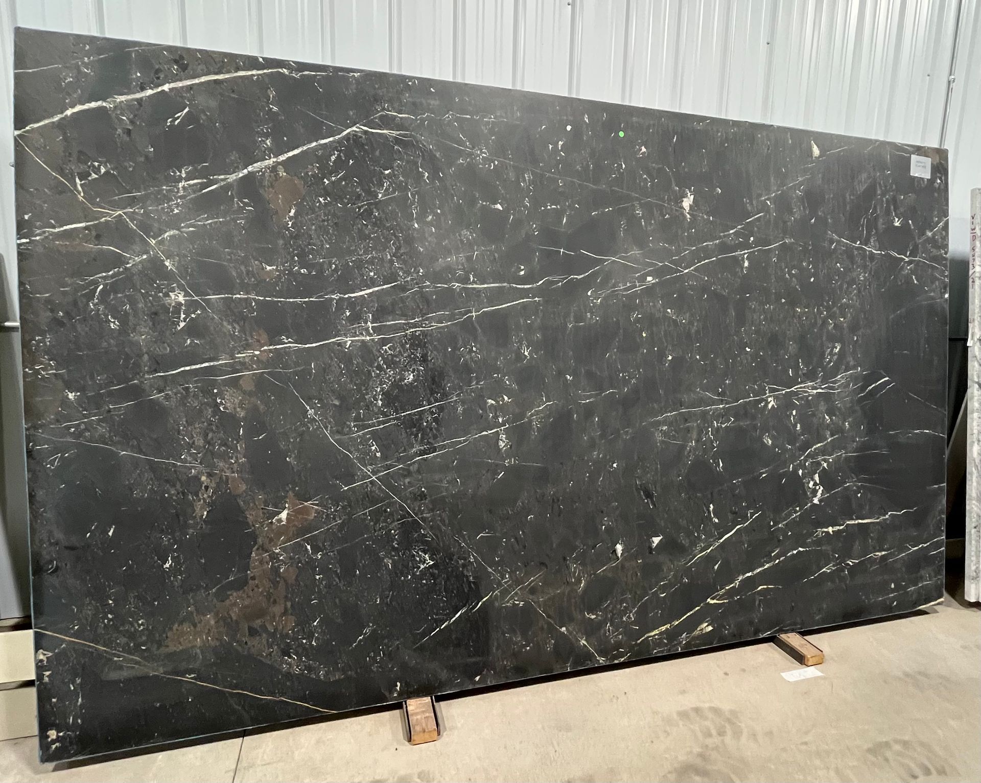 A large black marble slab is sitting on top of a cement floor.